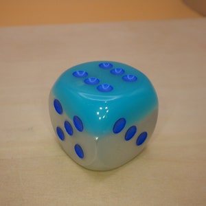 May include: A blue and white dice with blue dots on each side.