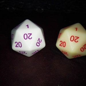 May include: Two twenty-sided dice. One die is white with purple numbers, the other is off-white with red numbers. Each die has the number 1 and the number 20 visible. The dice are for tabletop role-playing games.