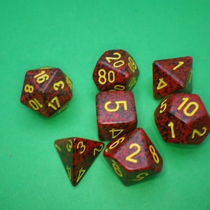 May include: A set of seven red and black dice with yellow numbers. The dice are a d4, d6, d8, d10, d12, and d20.
