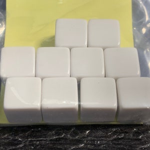 May include: Nine white ceramic square dice, arranged in a pyramid shape.
