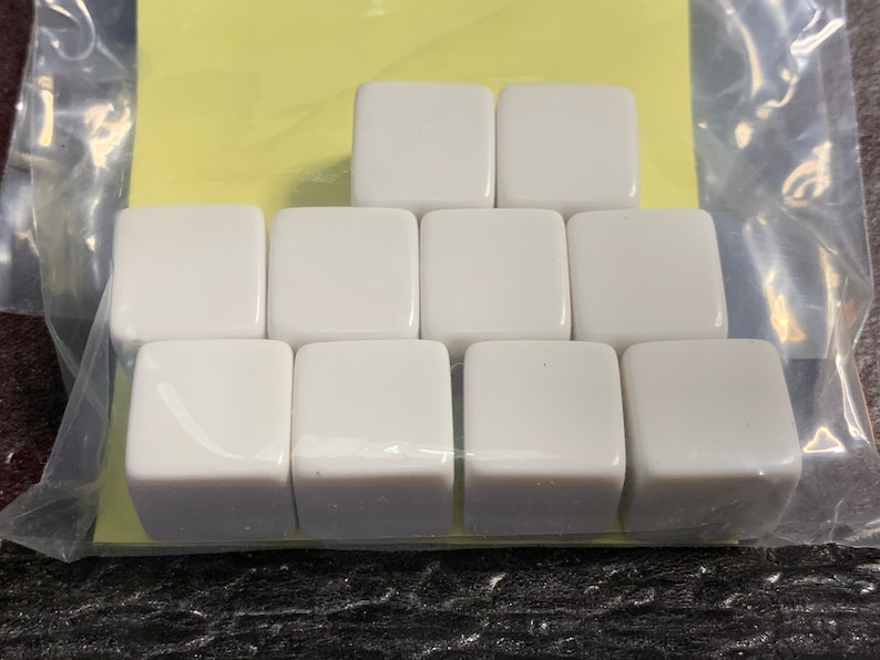 May include: Nine white ceramic square dice, arranged in a pyramid shape.