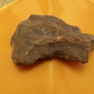 May include: A brown, irregularly shaped stone with a rough texture. The stone has a light brown color with darker brown patches.