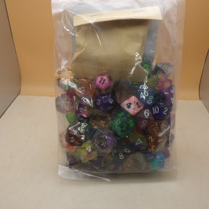 May include: A plastic bag filled with a variety of colorful dice with different numbers on each side. The dice are in a variety of colors, including red, blue, green, purple, and yellow.