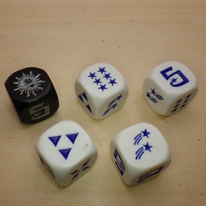 May include: Five white dice with blue markings. One die has a sun symbol, one die has a number 5, and three dice have shooting stars.