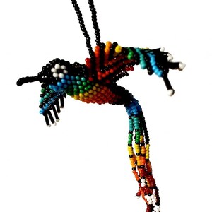 May include: A handcrafted hummingbird pendant necklace made of colorful beads. The bird features a black beak, head, and tail, with a body of rainbow-colored beads. The necklace is suspended from a black beaded chain.