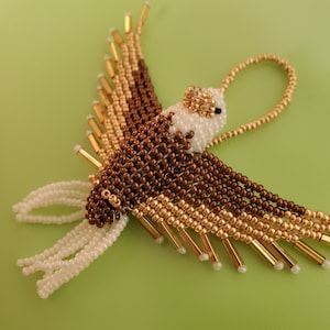 May include: A beaded eagle ornament with white, brown, and gold beads. The eagle has a loop at the top for hanging.