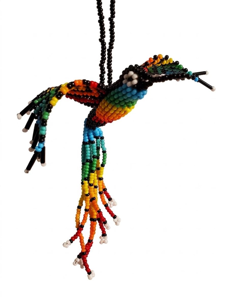 May include: A beaded hummingbird ornament in a vibrant array of colors, including red, orange, yellow, green, blue, and black. The bird's body and wings are meticulously crafted with small beads, and it hangs from a black beaded string.