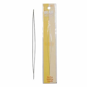 May include: A single, long, dark gray Big Eye Beading Needle is displayed next to its packaging. The packaging is a clear plastic sleeve with a yellow and beige label that reads "The Bead Smith" and "Big Eye Beading Needle."