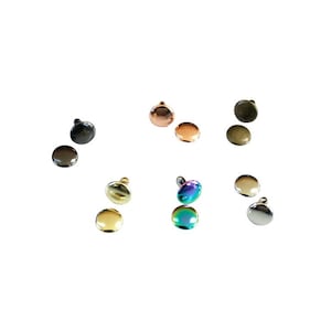 May include: A collection of six pairs of round metal rivets in various finishes including gunmetal, copper, antique brass, gold, iridescent rainbow, and polished silver. Each rivet features a smooth, domed top and a small metal post.