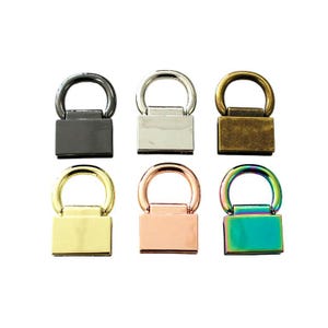 May include: A set of six metal bag strap connectors, each featuring a rectangular base and a circular ring. The finishes include matte black, polished silver, antique brass, bright gold, rose gold, and a multi-colored iridescent rainbow.