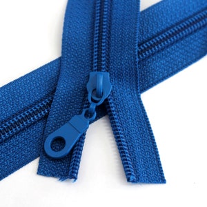 May include: A close-up of a blue zipper with a blue slider. The zipper is open and the slider is in the middle of the zipper.