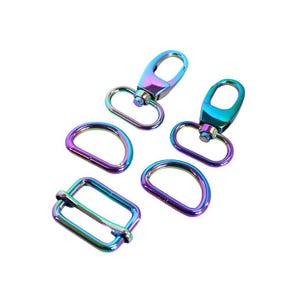 May include: A set of metal hardware components featuring a vibrant iridescent rainbow finish. The collection includes two swivel lobster claw clasps, two D-rings, and one rectangular slider buckle, all displaying a metallic gradient.