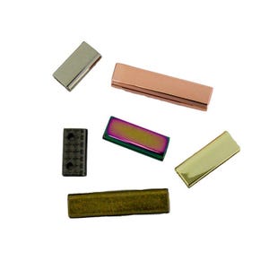 May include: A collection of six rectangular metal hardware components in various finishes including silver, rose gold, iridescent purple and green, gold, dark bronze, and a textured black piece with two small circular holes.