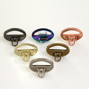 May include: Six oval-shaped metal clasps with a ring on the bottom. The clasps are in different colors: black, iridescent, copper, brass, gold, and silver.