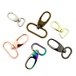 May include: A collection of six metal lobster claw clasps in various finishes, including silver, antique bronze, gold, rose gold, iridescent rainbow, and gunmetal gray, each featuring a swivel base and a spring-loaded gate mechanism.