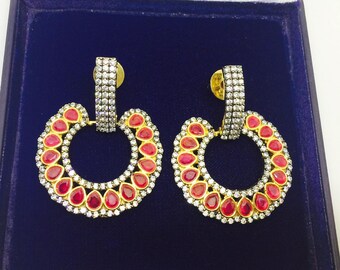 Boucles d'oreilles grands belles en tone dorée avec les strass blanc et rouge framboisee en forme de gouttes.