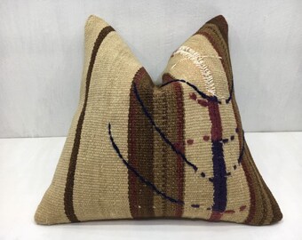 May include: A decorative pillow with a striped pattern in shades of brown, beige, and red. The pillow has a unique design with a dark blue and white abstract pattern.