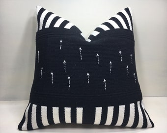 May include: A square decorative cushion with a black background and white accents. The cushion features white vertical stripes on the top and bottom edges. Small white arrows are embroidered on the black centre. The cushion is approximately 45 cm square.