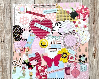 May include: A scrapbook page with a variety of decorative paper elements. The design includes a red heart with the word "LOVE", a pink butterfly, and the text "#lifemoments" and "#lucky". The color palette is primarily pink, red, and yellow.