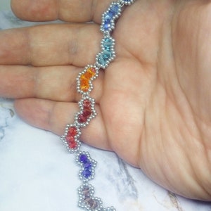 May include: A rainbow-coloured beaded necklace with silver accents. The beads are arranged in a zig-zag pattern.