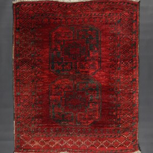 May include: A red rug with a black geometric pattern. The rug has a fringe border.