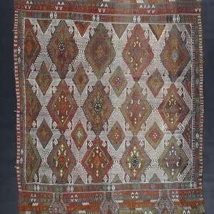 May include: A traditional Moroccan rug with a geometric pattern in shades of red, brown, white, and green. The rug has a fringe border.