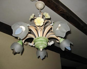 May include: A white and green floral chandelier with six frosted glass shades in the shape of bells. The chandelier has a floral design with yellow, white, and green flowers.