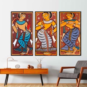May include: Three framed paintings depicting women in traditional Indian clothing. The women are depicted in a stylized, colorful manner with floral backgrounds. The paintings are framed in dark wood.