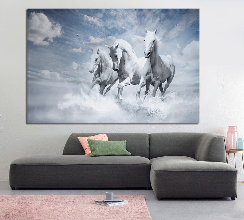 May include: Four white horses run through a misty, cloudy landscape. The horses are in mid-stride, with their manes flowing in the wind. The background is a soft blue with white clouds.