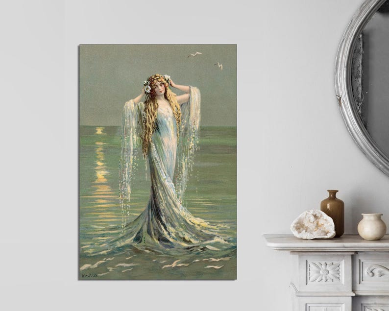 May include: A woman with long blonde hair wearing a flowing white dress stands in the ocean. The water is a light blue and green color, and the sky is a light blue. The woman is looking to the right, and her hair is flowing in the wind.
