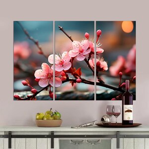 May include: A three-panel canvas print featuring a close-up of pink cherry blossoms in bloom against a blurred background of green leaves and a sunset.