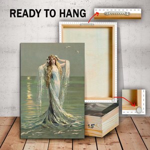 May include: A vintage-style canvas print of a woman with long flowing hair, wearing a flowing white dress, standing in the ocean. The print is ready to hang and has a 1.5 inch deep frame.