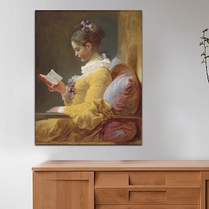 May include: A painting of a woman in a yellow dress sitting in a chair and reading a book. The woman has her hair pulled back and is wearing a white lace collar. The painting is done in a soft, muted palette.