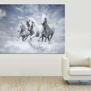 May include: Four white horses run through a cloudy sky, creating a sense of freedom and movement. The horses are in mid-stride, with their manes flowing in the wind. The background is a soft blue with white clouds.