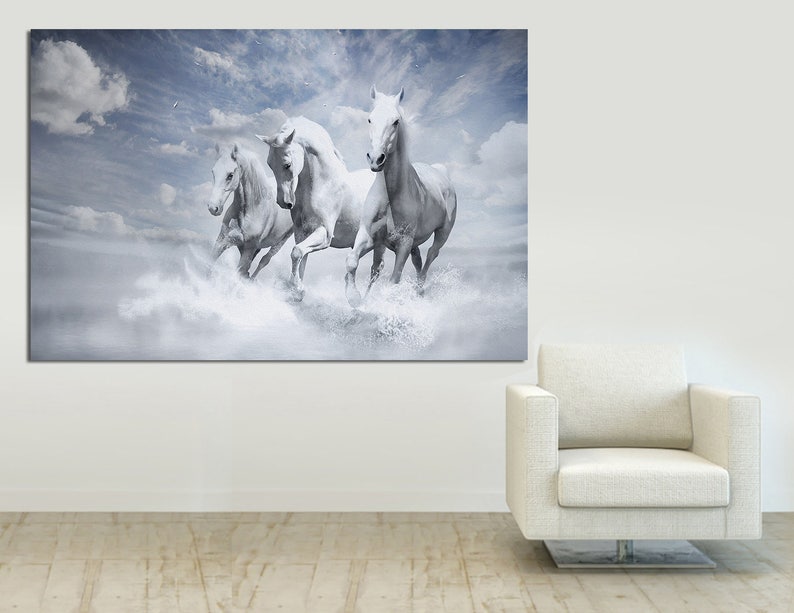 May include: Four white horses run through a cloudy sky, creating a sense of freedom and movement. The horses are in mid-stride, with their manes flowing in the wind. The background is a soft blue with white clouds.