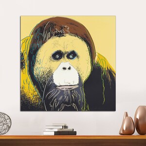 May include: A close-up portrait of an orangutan with a yellow, green, and blue background. The orangutan's face is in focus, with its eyes, nose, and mouth clearly visible. The orangutan's fur is dark brown and appears to be thick and soft.