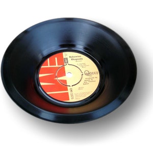 Könnte beinhalten: Eine schwarze Schallplatte mit einem rot-weißen Label. Das Label zeigt den Text "Bohemian Rhapsody" und den Bandnamen "Queen". Die Schallplatte ist eine 7-Zoll-Single, ein klassisches Musikformat.