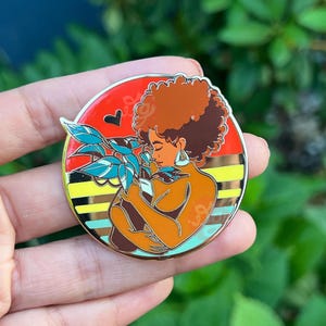 Hard Enamel Pin with black woman cradling plant like a child.