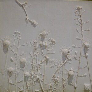 May include: White plaster relief sculpture of a group of wild flowers, including daisies and other delicate blooms. The flowers are arranged in a natural, flowing pattern, creating a sense of movement and life. The sculpture is a beautiful and unique piece of art that would add a touch of nature to any home.