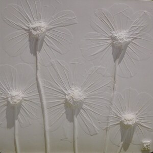 May include: White textured wall art featuring five raised, embossed white flowers. The flowers are stylized and resemble daisies.