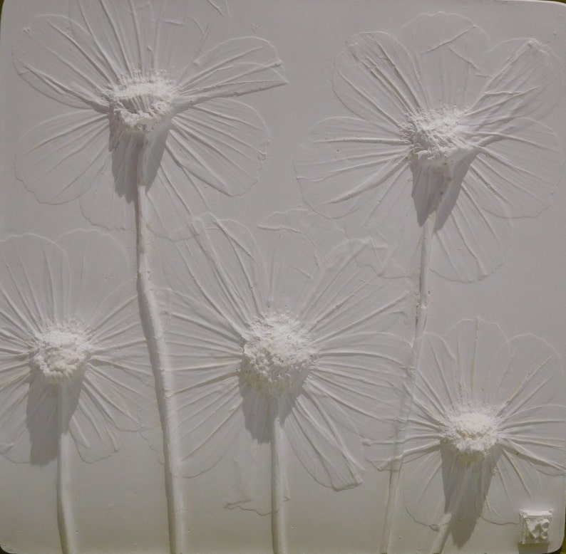 May include: White textured wall art featuring five raised, embossed white flowers. The flowers are stylized and resemble daisies.