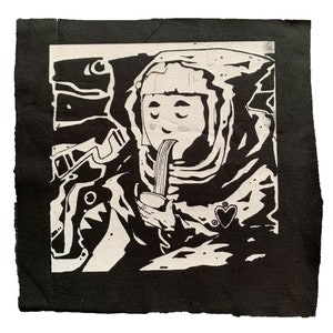 May include: Black and white illustration of an astronaut wearing a helmet and eating noodles from a cup. The astronaut is wearing a heart-shaped pendant.