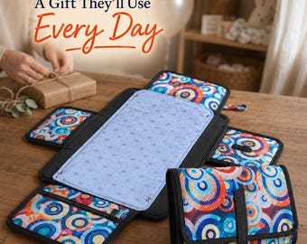 May include: A portable changing mat featuring a light blue center panel with a small star pattern, surrounded by black-trimmed flaps with a vibrant, multi-colored circular pattern. The text A Gift They'll Use Every Day is visible above.