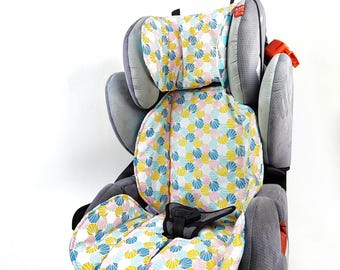 May include: A gray car seat featuring a removable padded liner with a repeating geometric fan pattern in yellow, blue, and pink. The seat includes adjustable headrest wings, a central harness buckle, and textured gray fabric on the side panels.