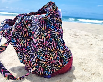 May include: A black beach bag with a colorful geometric pattern. The bag has a mesh pocket and a small label that says "Market Bag".