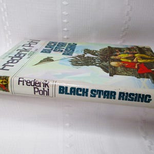 Puede incluir: Un libro de bolsillo vintage titulado "Black Star Rising" de Frederik Pohl. La portada presenta una colorida ilustraci&oacute;n de figuras en un paisaje rocoso. El t&iacute;tulo del libro y el nombre del autor se muestran prominentemente en azul y blanco.