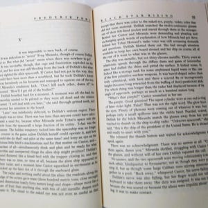 Puede incluir: Libro abierto con texto en las p&aacute;ginas. El libro se titula "Black Star Rising" de Fredric Pohl. Las p&aacute;ginas est&aacute;n amarillentas por el tiempo, y se ve una mano que sostiene el libro abierto. El texto est&aacute; en ingl&eacute;s.