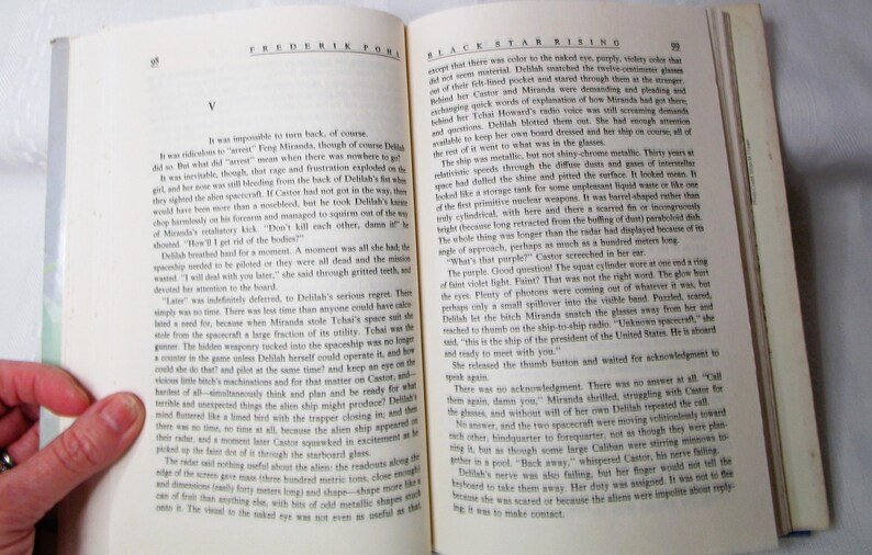 Puede incluir: Libro abierto con texto en las p&aacute;ginas. El libro se titula "Black Star Rising" de Fredric Pohl. Las p&aacute;ginas est&aacute;n amarillentas por el tiempo, y se ve una mano que sostiene el libro abierto. El texto est&aacute; en ingl&eacute;s.