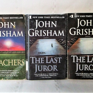 May include: Three hardcover books by John Grisham are displayed. The titles are "Bleachers" with a stadium scene, and "The Last Juror" with a table scene. Each book is a New York Times bestseller.