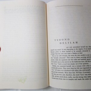 Puede incluir: Libro abierto con texto en la p&aacute;gina derecha y una mano sosteniendo la p&aacute;gina izquierda. El texto dice "TSOONG DELILAH". Las p&aacute;ginas del libro son de color blanquecino con texto negro.